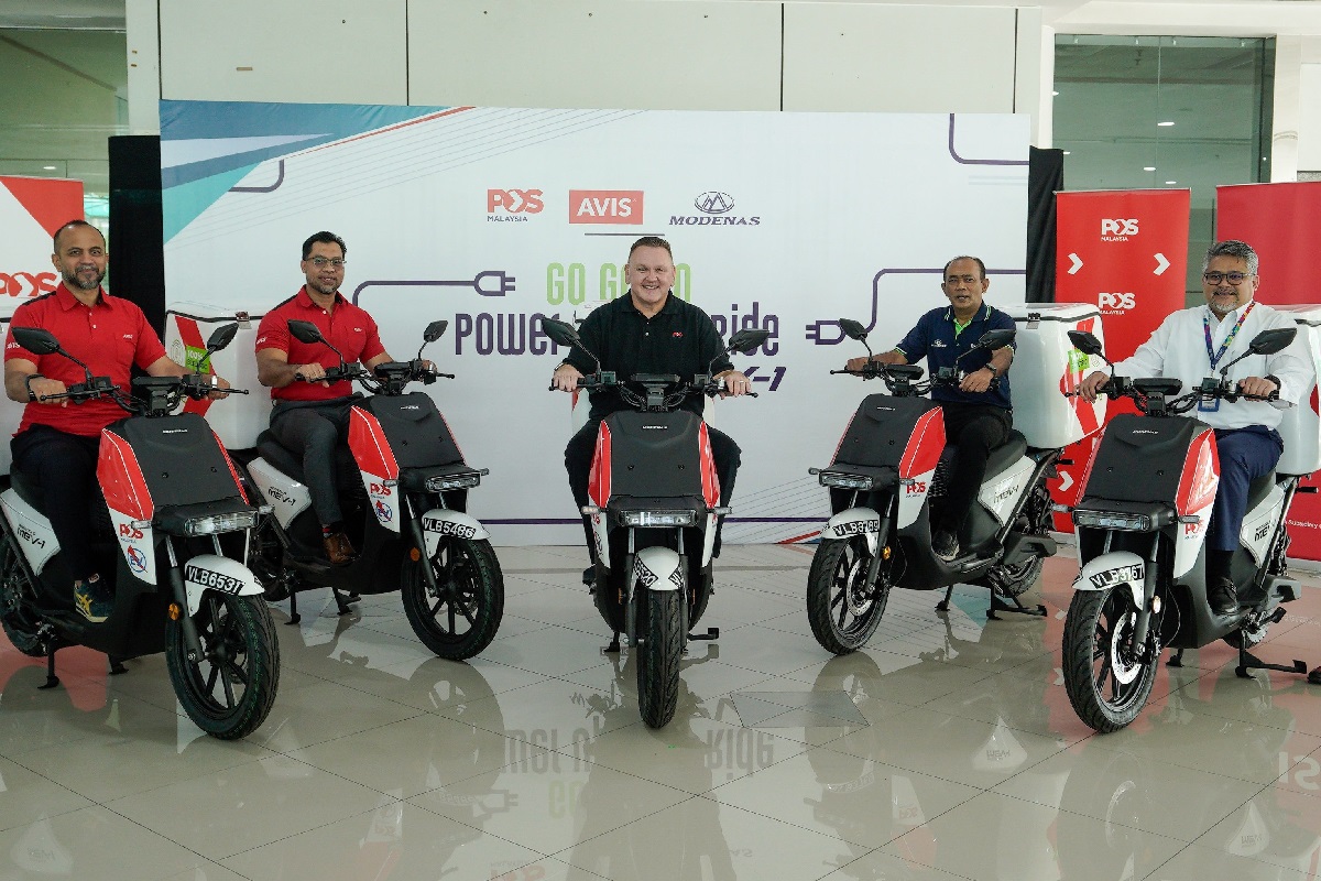 Leading by example: Charles Brewer (centre) on one of Pos Malaysia's new e-bikes