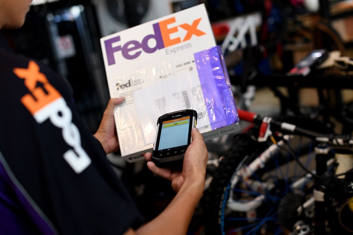 A FedEx worker scans an e-commerce package